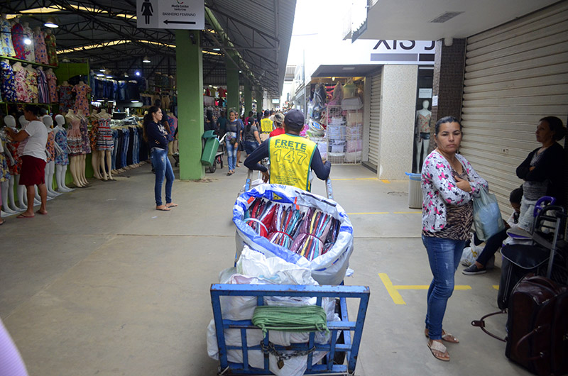 Pessoas trabalham levando as compras dos comerciantes